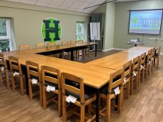Room with tables, chairs and a large screen