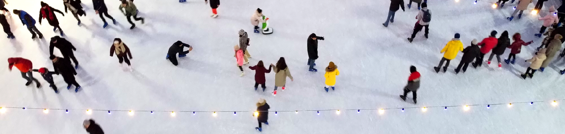 Ariel view of an ice rink with people dressed in coats, hats and scarves skating around