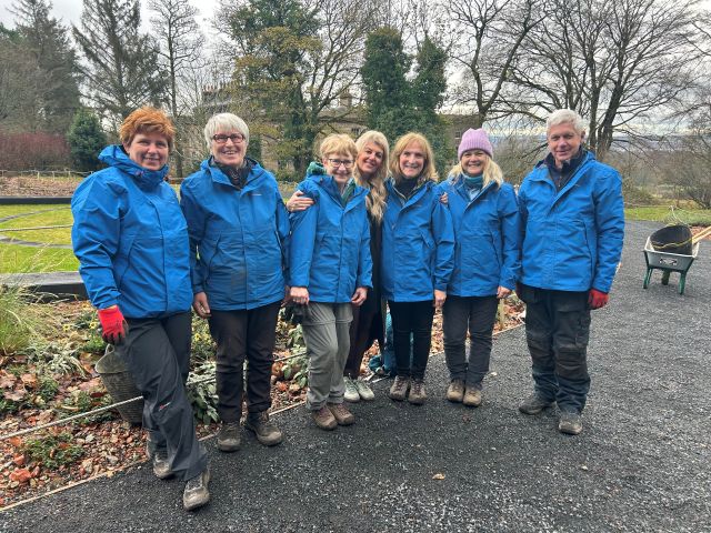 A group of Haigh Hall Volunteers with blue jackets stood in the grounds